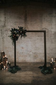 a wedding arch with candles and greenery in front of an old concrete wall at night