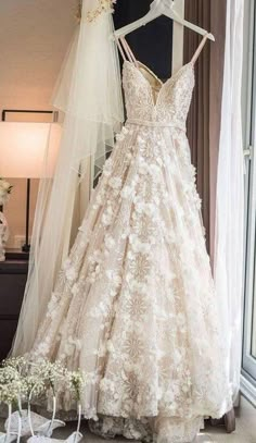 a wedding dress and veil are on display in front of a window with white flowers