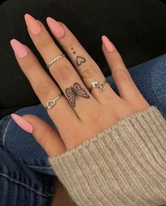 a woman's hand with four different tattoos on her fingers and two rings in the middle