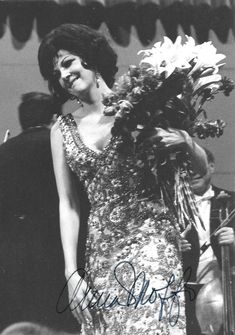 an old black and white photo of a woman in a sequin dress holding flowers