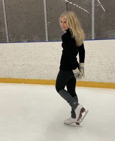 a woman skating on an ice rink wearing winter clothing and gloves with her hands behind her back