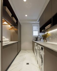 a washer and dryer in a small room with white marble flooring on the walls