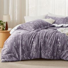 a bed with purple comforter and white pillows