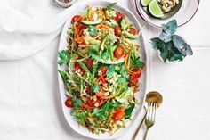 a white plate topped with salad next to two bowls filled with vegetables and dressings