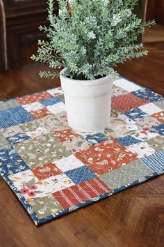 a potted plant sitting on top of a patchwork table cloth covered in fabric