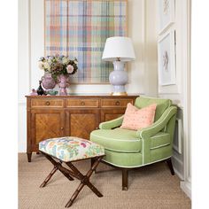 a green chair sitting in front of a wooden dresser with a lamp on top of it