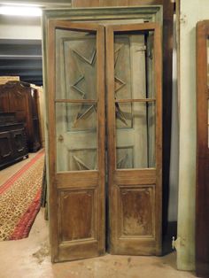 an old wooden door with glass panels on the front and back doors, sitting in a room