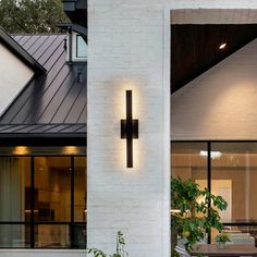 a white house with a cross on the wall and plants growing in pots next to it