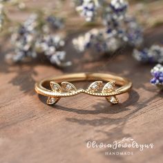 a close up of a ring on a wooden surface with lavender flowers in the background