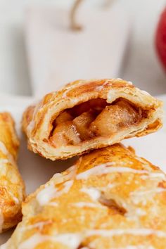 two apple hand pies sitting on top of a white plate next to an apple