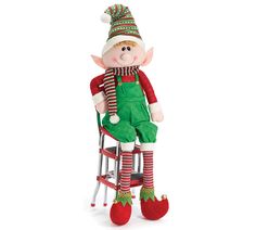 a christmas elf doll sitting on top of a chair with his legs crossed and feet up