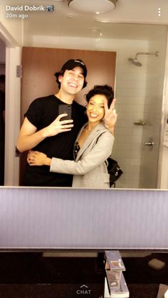 a man and woman standing in front of a bathroom mirror with their arms around each other