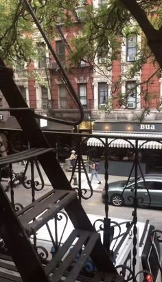 the view from an apartment balcony looking down at cars and people walking on the street