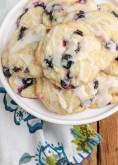 a white bowl filled with blueberry cookies covered in icing