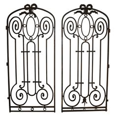 two wrought iron gates with decorative designs on the top and bottom, set against a white background