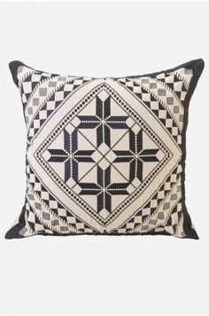 a black and white pillow with an intricate design on the front, sitting against a white background