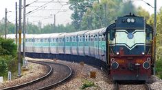 a train is traveling down the tracks near some trees and bushes on either side of it