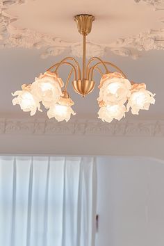 a chandelier hanging from the ceiling in a room with white walls and curtains