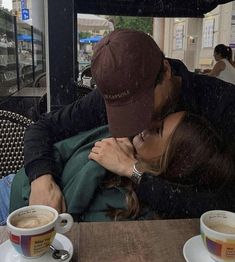 a man and woman kissing in front of two cups of coffee