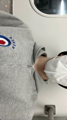 a person wearing a face mask standing next to an airplane window with the word pepsi on it