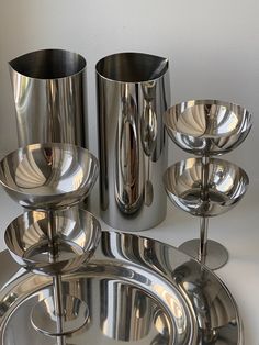 a group of silver cups and saucers sitting next to each other