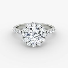 a round brilliant cut diamond ring with halos on the shoulders and sides, set in 18k white gold