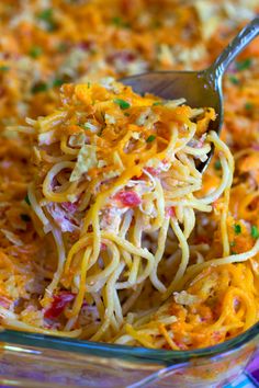 a close up of a spoon in a casserole dish with noodles and cheese