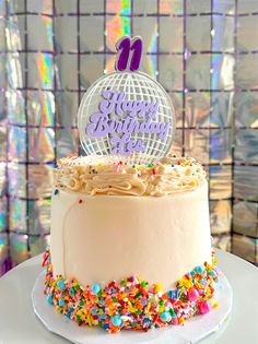 a birthday cake with sprinkles and a disco ball topper on it