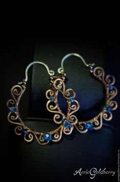 a pair of gold hoop earrings with blue stones on it's earwires