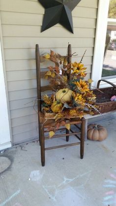 a wooden chair sitting on top of a porch next to a star and pumpkins