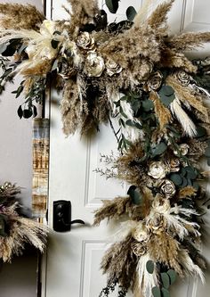 a wreath made out of feathers and flowers on the front door to a home in winter