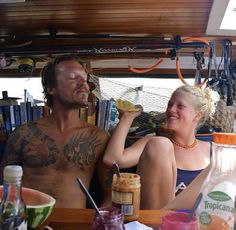 a man and woman sitting on a boat with food in front of their faces,