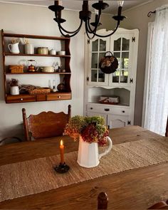 a dining room table with a white pitcher on it and a candle in the center