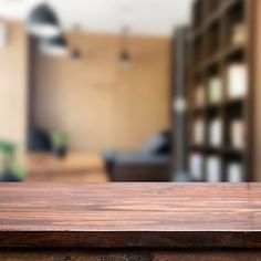 a wooden table top in front of a blurry living room with bookshelves