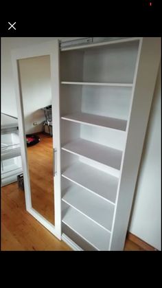 an empty white bookcase in the corner of a room