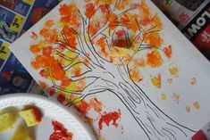 a paper plate with some food on it next to a tree and other art supplies