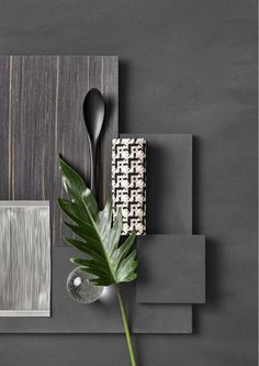 a black table topped with a green plant next to a gray wall