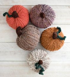 four knitted pumpkins sitting on top of a wooden floor