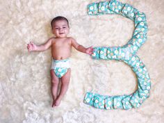 a baby laying on top of a white rug next to the number five shaped like an elephant