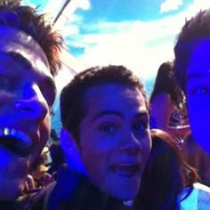 three young men standing next to each other in front of a blue sky and clouds