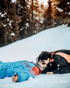 a man and woman laying in the snow