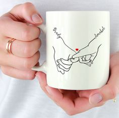 a woman holding a coffee mug with two hands and a heart on the inside of it