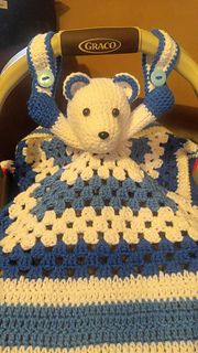 a crocheted teddy bear is sitting in a stroller