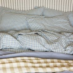 an unmade bed with blue and white checkered sheets