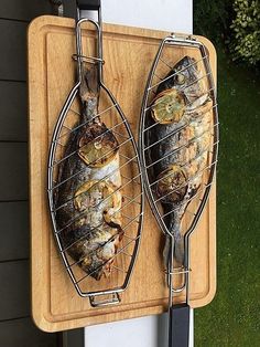 two grilled fish sitting on top of a wooden cutting board next to a window