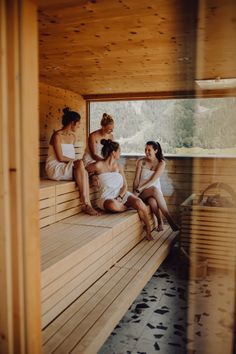 four women sitting in a sauna with their backs turned to the side and looking out