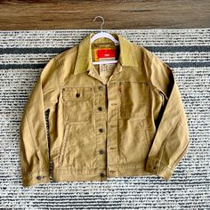 Brand New With Tags, Levi Stock Trucker Jacket. Size Small, Fits Like A Medium Levi's Long Sleeve Utility Outerwear, Levi's Collared Outerwear With Button Closure, Levi's Khaki Outerwear With Pockets, Levi's Long Sleeve Utility Jacket For Fall, Levi's Brown Outerwear For Spring, Levi's Workwear Outerwear With Flap Pockets, Levi's Button-up Outerwear With Pockets, Brown Levi's Outerwear For Spring, Levi's Collared Outerwear For Fall