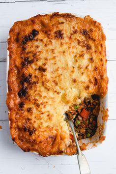 a casserole dish with meat and vegetables being lifted from the casserole