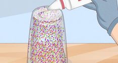 a person is pouring something into a glass container with sprinkles on it