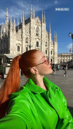 a woman with red hair and glasses in front of a cathedral